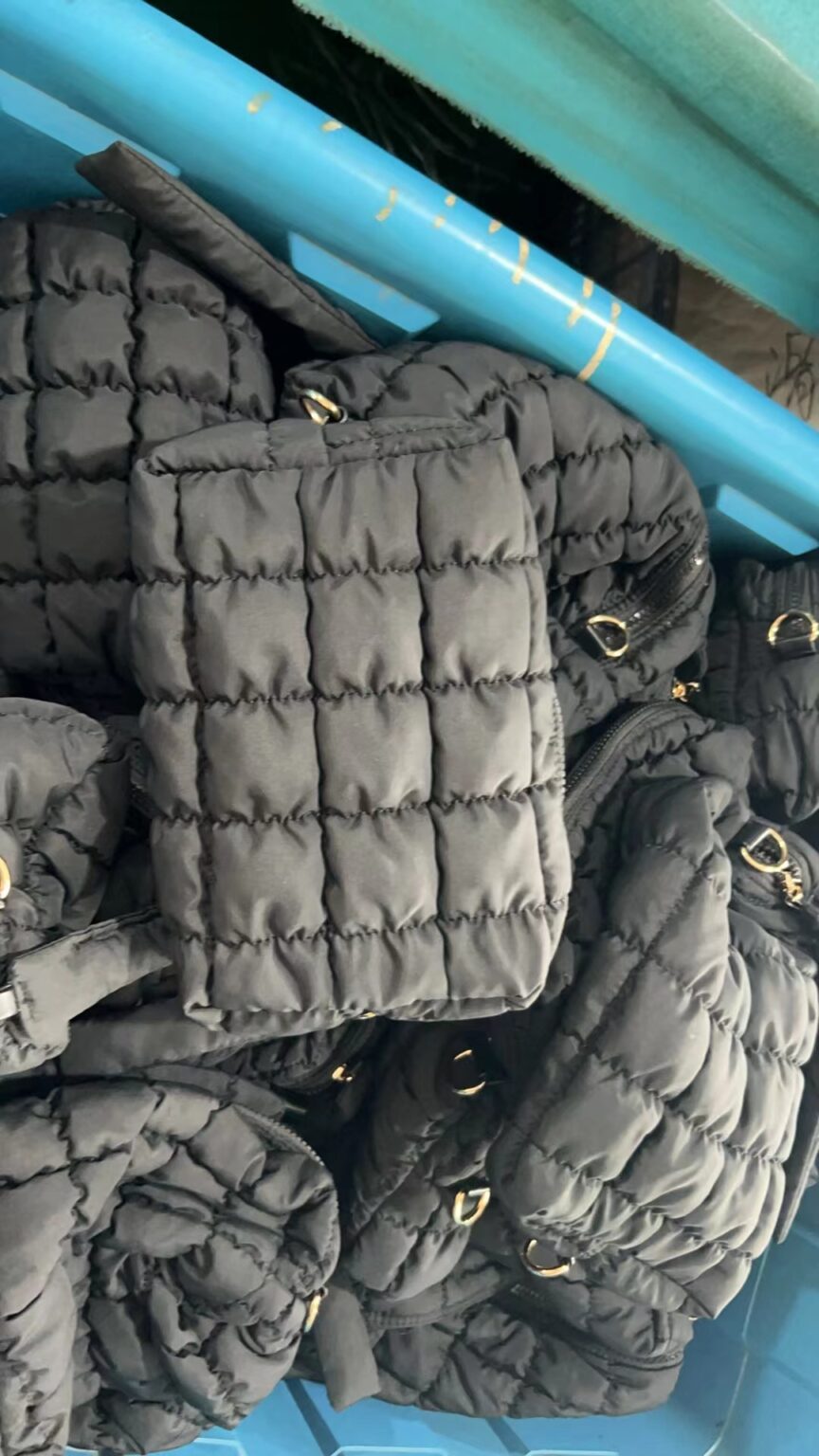 Black quilted zip pouches in a production batch, showing stitched panels and zipper details