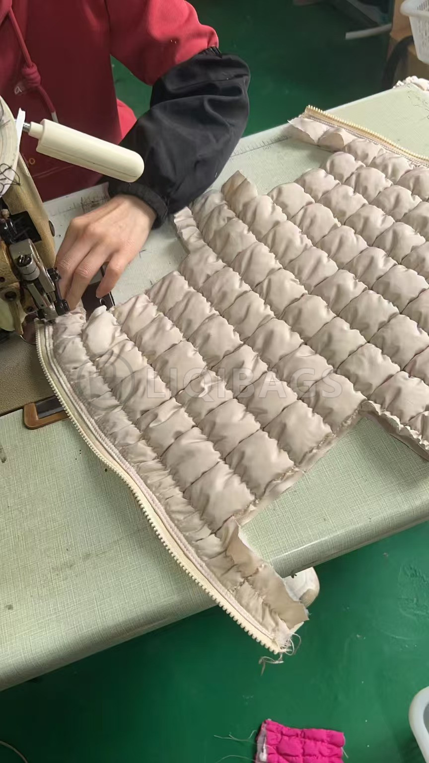 Sewing a padded quilted cosmetic bag panel along the zipper edge on an industrial sewing machine